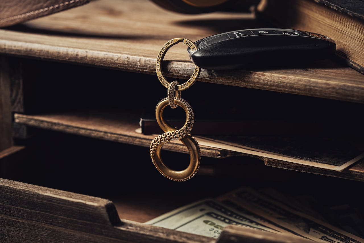 Elegant infinity symbol keychain with car key on rustic wooden desk, conveying sophistication and luxury.